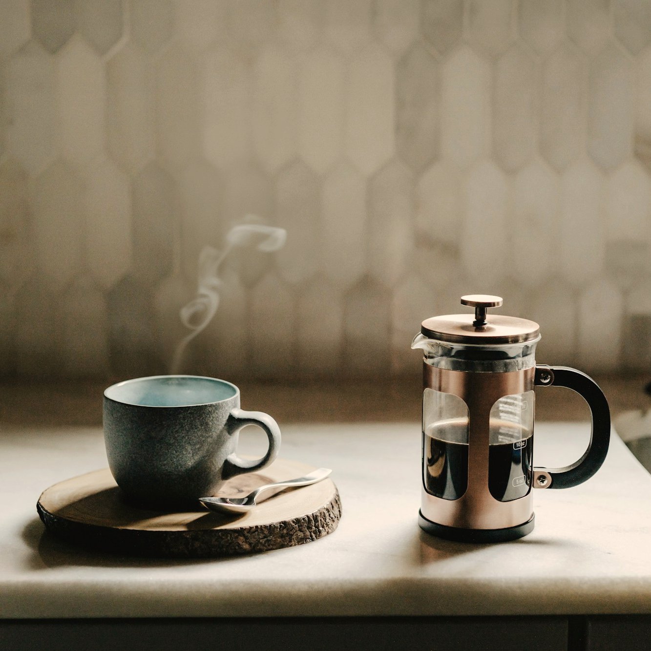 Taza de café humeante junto a una prensa francesa